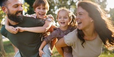 Happy family of four enjoying a playful piggyback ride outdoors.