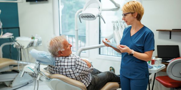Dentist consulting elderly patient in dental office.
