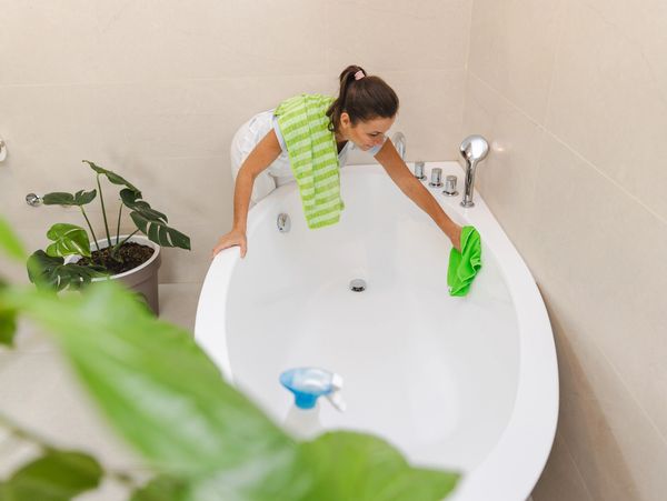 Person cleaning bathtub with tools