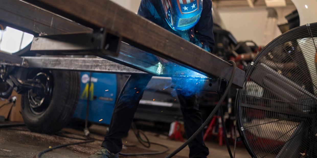 A person welding a metal frame inside a workshop.