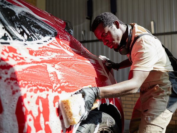 Man washing red car exterior.