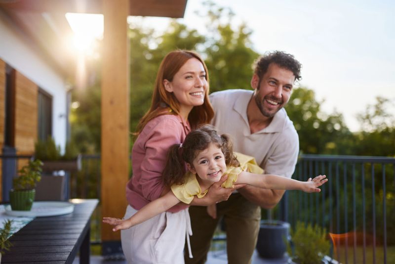Happy parents having fun while playing wit their little daughter during springtime on a patio.