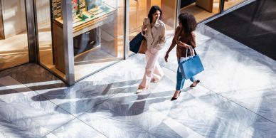 Two women walking with shopping bags outside a store.