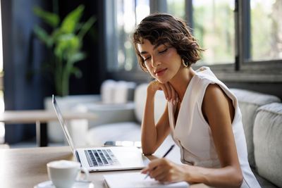 Woman working on a laptop and taking notes.