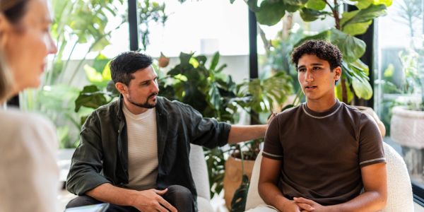 Man supports young man during emotional talk.