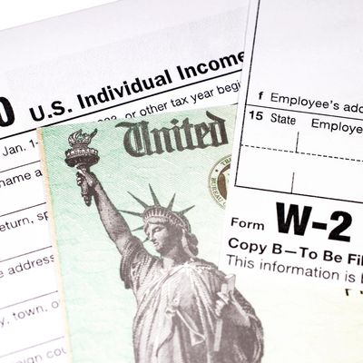 Tax forms and a U.S. dollar bill with the Statue of Liberty.
