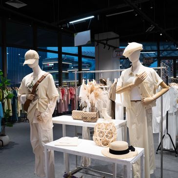 Mannequins dressed in beige fashion with accessories in a store.