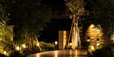 A nighttime garden pathway illuminated by warm garden lights.