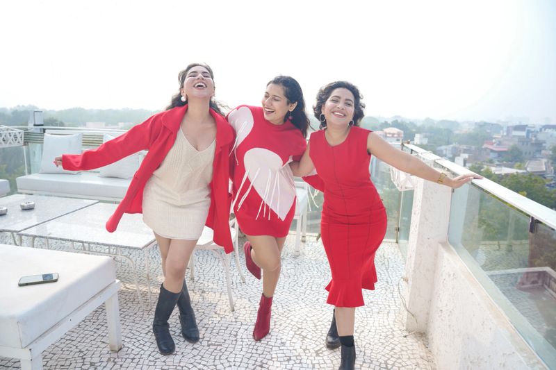 carefree beautiful indian Gen Z female friends wearing red outfit standing together outdoor. Bonding Friendship