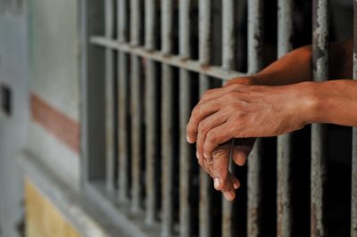 Hands gripping prison bars with a somber tone.