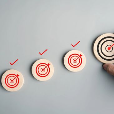 Hand placing a larger wooden disc with a target symbol, showing progress and achievement.