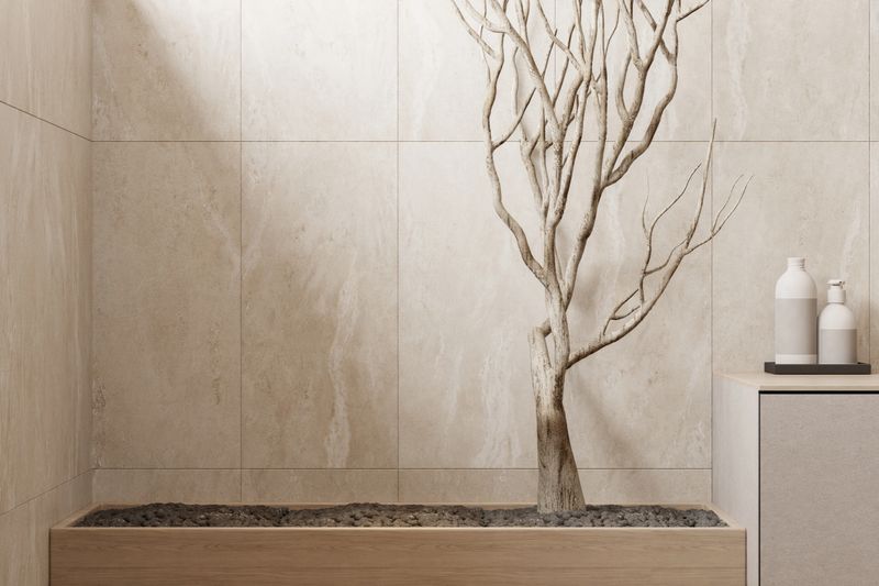 Modern Japandi style bathroom with natural beige stone tiles, floating vanity with round mirror, walk-in shower with black fixtures, and decorative wooden elements. Neutral colors, simple lines, and a mix of Japanese minimalism and Scandinavian coziness create a calm and elegant spa-like atmosphere. This image is ideal for illustrating concepts of interior design, bathroom renovation, modern home decor, wellness, relaxation, or architectural inspiration.