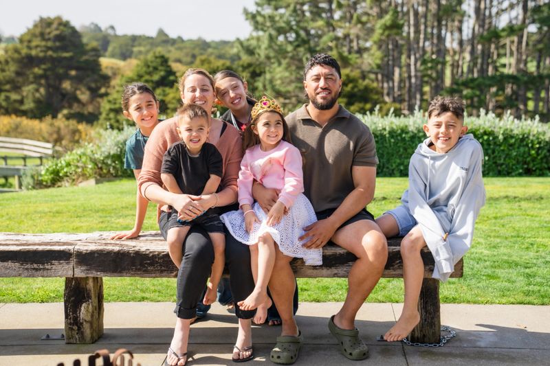A happy family enjoys quality time together outdoors, smiling at the camera and sharing a moment of love and togetherness in a green, natural setting.