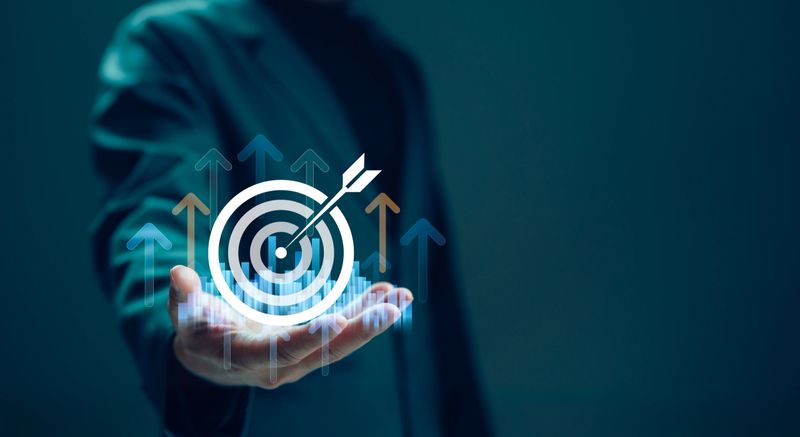 Businessman holds glowing dartboard icon symbolizing business objective, goal achievement, success. Concept shows strategy, ambition, challenge, purpose, vision, growth. Aiming high, reaching