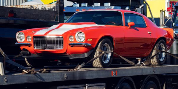 Classic red muscle car on a flatbed truck.