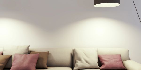 Cozy sofa with cushions under soft lamp light.