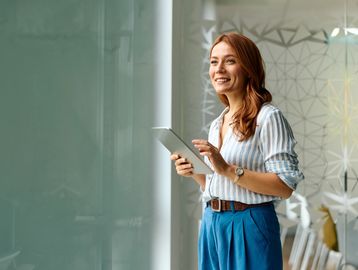 Young woman smiling while holding a tablet.