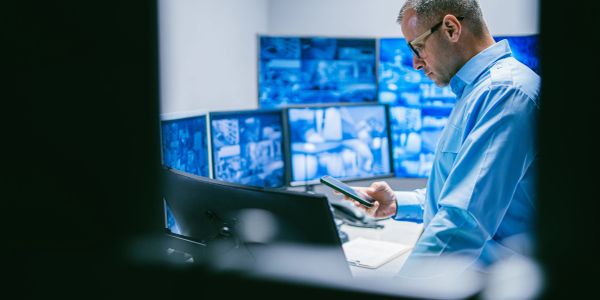 Man monitors security cameras using a smartphone.