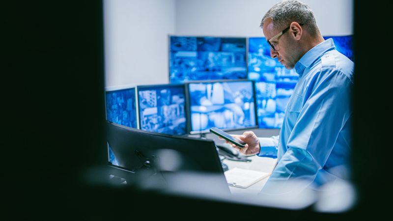 Security Male Operator  Reviewing Data in Control Room with Technology