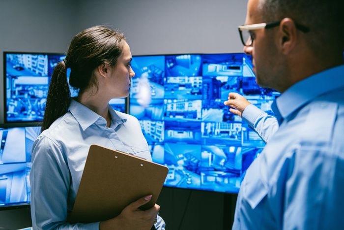 Two security personnel monitoring multiple surveillance screens. Alarm response, CCTV towers, Keyholding and construction site security control room