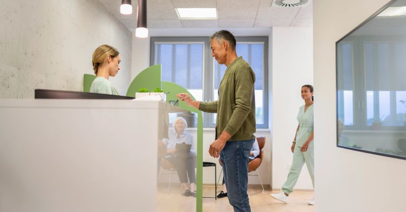 An adult man in a physiotherapy clinic receives instructions from a therapist on how to complete a questionnaire about his current health status. Health and care concept.