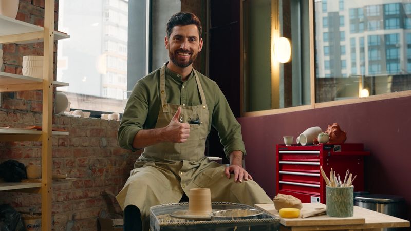 Happy creative smiling Caucasian artist entrepreneur man guy small business owner potter craftsman male looking at camera showing thumb up gesture recommend like hobby artwork indoor workshop studio. High quality 4k footage