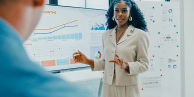A woman presenting data on a screen during a meeting.