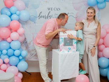 Family enjoying a gender reveal party with balloons.
