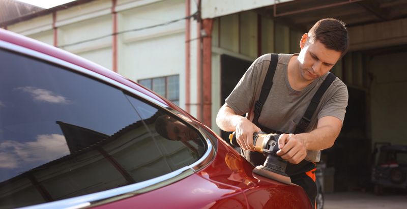 Man polishing car with orbital polisher outdoors