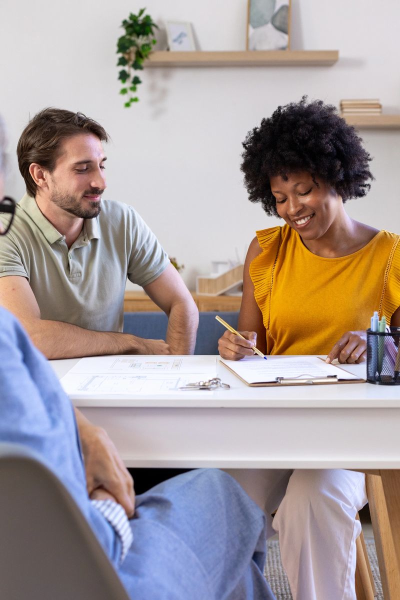 Diverse couple signing a home purchase contract with an agent, celebrating their new real estate investment