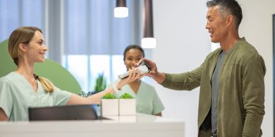 Man handing over a card to a receptionist.