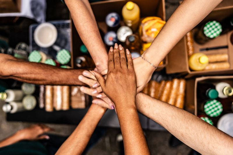 Close-up of people stacking hands over donation boxes