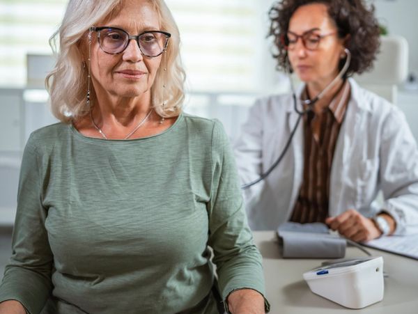 Senior woman getting her blood pressure checked by a female doctor in a clinic.