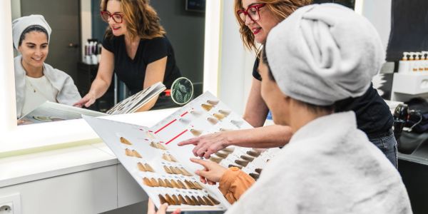 Woman and stylist choosing hair color at salon.