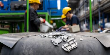 Workers sorting metal pieces on a conveyor belt.