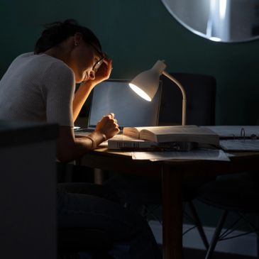 Woman studying late at night under a desk lamp.