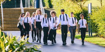 Group of students walking outdoors in school uniforms.
