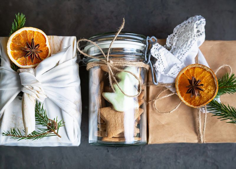 Christmas zero waste, rustic, eco. Three main eco-friendly gift wrapping - furoshiki style (cloth), craft paper, glass (jar). Boxes decorative dried oranges, anise, Christmas tree branch, handmade napkin.