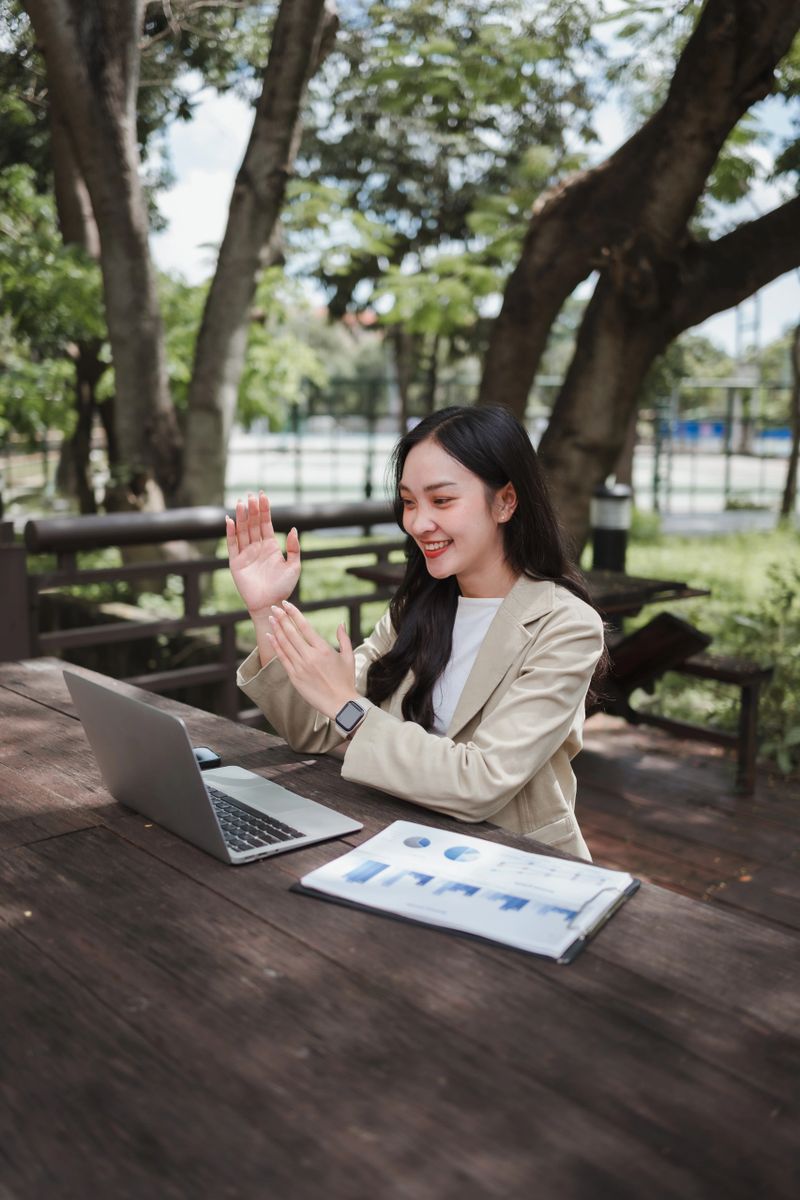 Young business woman on a video conference call, actively participating in a meeting while working remotely outdoors