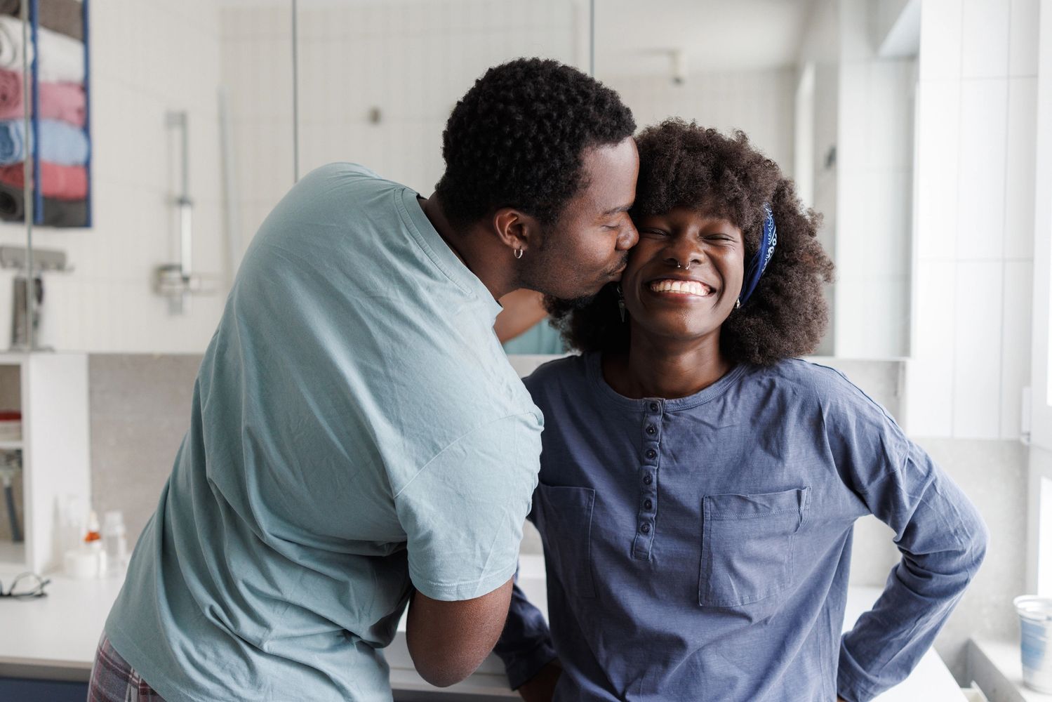 Smiling woman with curly hair wearing a blue patterned top.