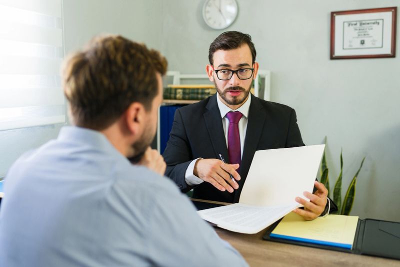 Professional lawyer providing legal advice to a male client, explaining important contract documents during an office consultation