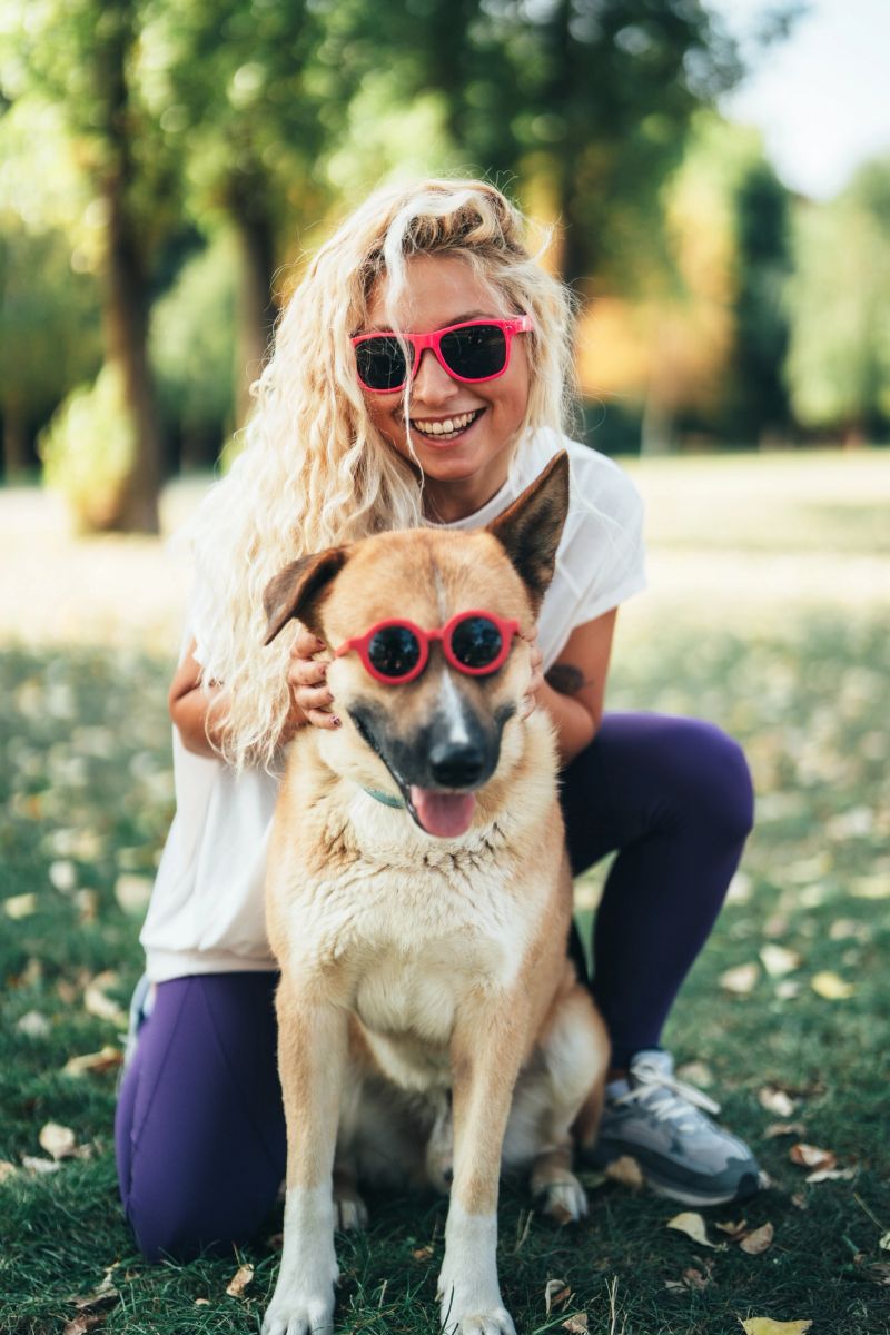 Happy moment with pet owner and her dog, wearing colorful sunglasses. Concept of friendship, fun, summer lifestyle, and pet love