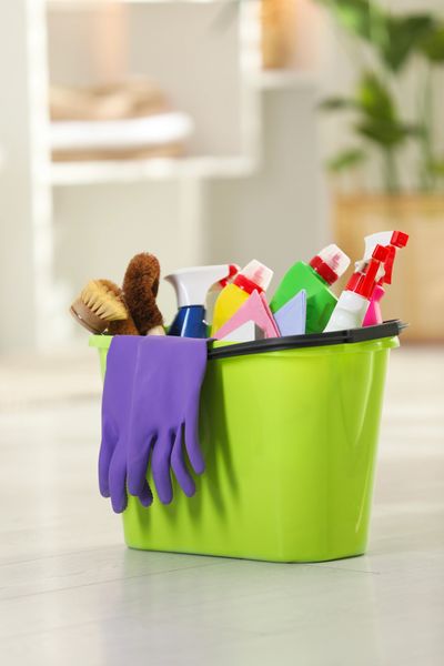 Green bucket filled with cleaning supplies and purple gloves.