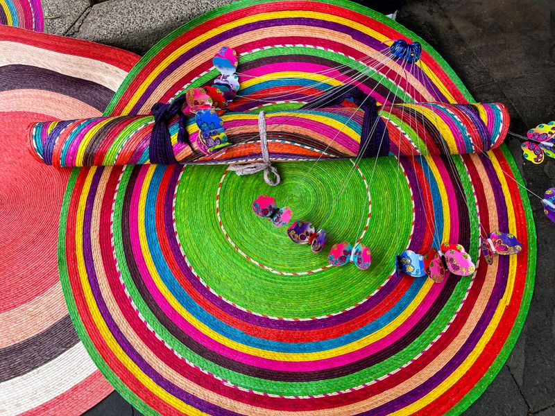 Detailed close-up of colorful handmade woven mats made with natural fibers, showcasing vibrant colors and artisanal craftsmanship from Mexico. Ideal for design, decoration, or texture backgrounds.