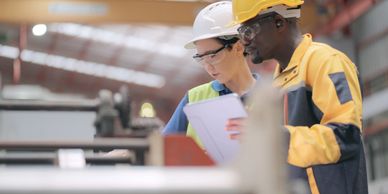 Two factory workers reviewing tablet data.