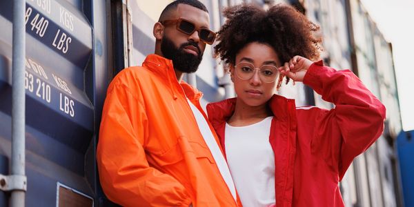 Stylish man and woman in bright jackets posing confidently outdoors.