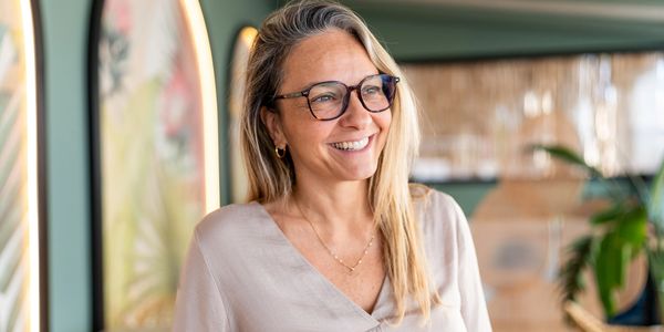 Smiling woman with glasses in a bright room.