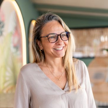 Smiling woman with glasses indoors.