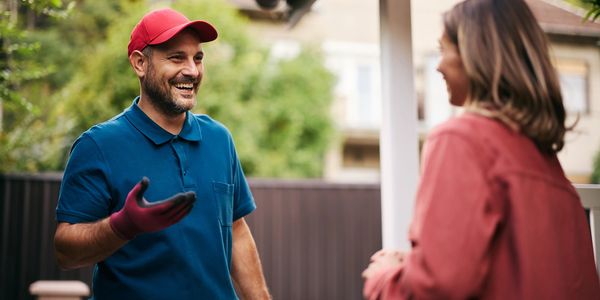 A gardener chatting happily with a woman outdoors.