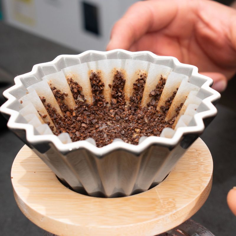 Close-up of a coffee filter filled with ground coffee, ready for brewing. Ideal for illustrating home coffee preparation, barista techniques, or artisanal coffee culture.